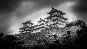 一座歷史悠久的日本城堡，位於石山上，天空多雲。