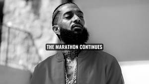 一個有鬍鬚和紋身的男人向上看，上面覆蓋著文字「THE MARATHON CONTINUES」。