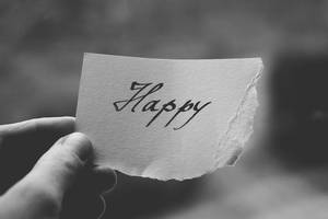 手拿撕破的紙，上面有手寫的 'Happy' 字樣，黑白配色。