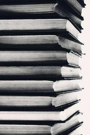 黑白垂直堆疊的書籍，書脊和書頁帶有紋理。