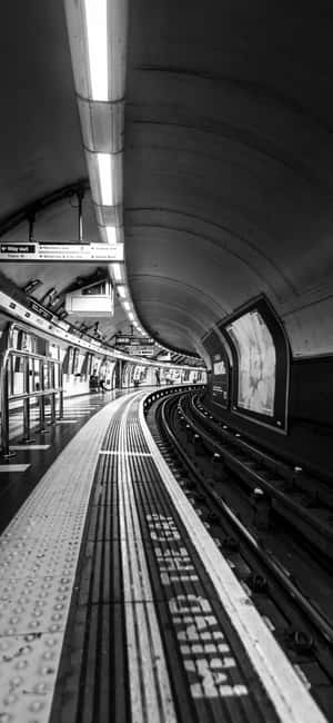 空蕩地鐵站月台連彎曲路軌的黑白景觀。 — 黑白 壁紙
