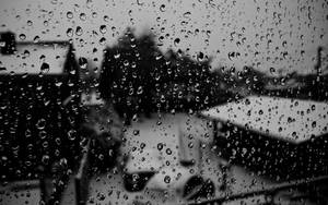 窗戶上的雨滴，外面模糊的屋頂和樹木。