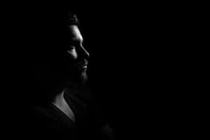男人側面，一側有強光，背景為黑色