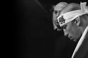 戴著漢字頭帶的相撲力士專注地向下看。