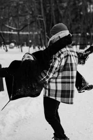 兩個人在雪中玩耍，其中一個在冬季公園被抬起 — 黑白 壁紙