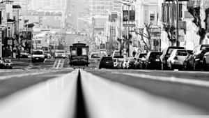 黑白照片顯示一輛纜車正在爬升一條停滿汽車的陡峭城市街道。