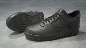 灰色混凝土地板上的兩對黑色Nike Air Force 1運動鞋。 — 低飽和度 壁紙