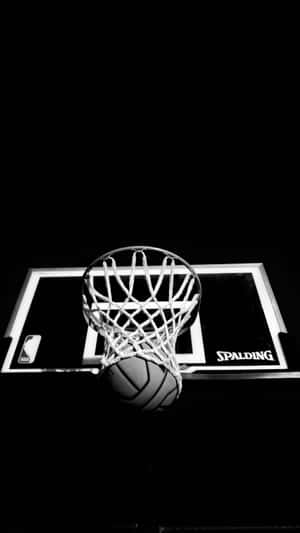 一個籃球卡在帶有 Spalding 標誌的籃框中，背景為黑色。
