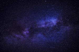 銀河系在深紫色和藍色中閃耀，映襯著繁星點點的夜空。 — 黑紫 壁紙