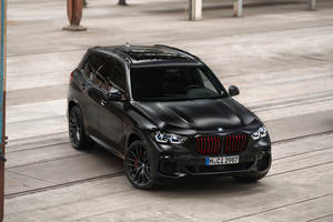 啞光黑色BMW X5 M Competition SUV，帶紅色飾件，停泊在工業環境中。 — Audi R8 GIF 壁紙