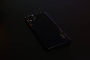 一部黑色 OPPO 智能手機，帶有光面機身，放置在黑暗的表面上。