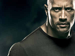 Dwayne Johnson 身穿深色T恤，表情嚴肅凌厲。 — 暗色 壁紙