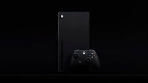 黑色 Xbox Series X 主機和控制器放在黑暗表面上。
