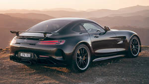 黑色Mercedes-AMG GT跑車停在日落時分的山頂觀景點。