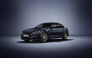 深藍色BMW M3轎車，金色輪圈，在工作室環境中。
