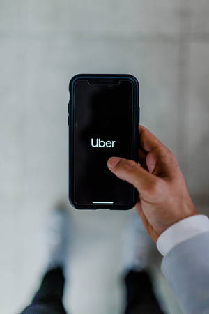 手拿著手機，屏幕上顯示Uber應用程式標誌