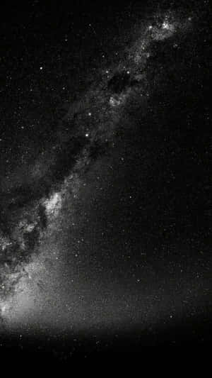 銀河系在繁星點點的夜空中以黑白色彩閃耀。 — 黑色 iPhone 壁紙