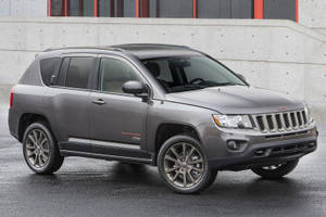 灰色Jeep Compass SUV停泊在濕漉漉的路面上，靠近帶有紅色點綴的混凝土牆。 — 汽車 壁紙