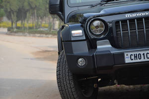 黑色Mahindra Thar SUV在塵土飛揚的道路上的正面視圖 — 汽車 壁紙