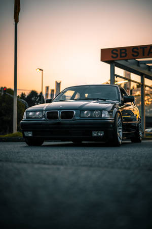 黑色BMW轎車在金色日落時分停靠在加油站。