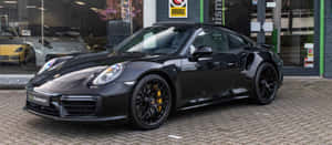 黑色保時捷911 Turbo S，配備黃色制動卡鉗，停在汽車經銷商外。