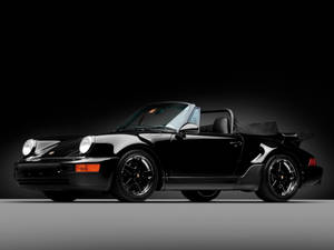 黑色保時捷911 Turbo開篷跑車在攝影棚中，帶有戲劇性燈光。