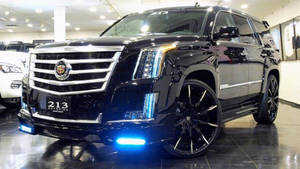 黑色 Cadillac Escalade 配備定制輪圈和藍色燈光，在展廳中。