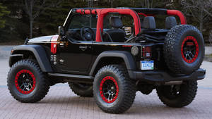 黑色Jeep Wrangler，紅色輪胎，停在磚砌車道上
