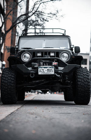 黑色改裝Jeep Wrangler停泊在城市街道上，帶有科羅拉多州車牌。