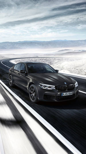 啞光黑色BMW M5 RS在沙漠高速公路上飛馳，遠山在望。