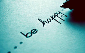 手在藍色紙上書寫「be happy」和心形。