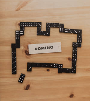 黑色多米諾骨牌在木質表面上形成矩形，內部有「DOMINO」標籤。 — Vivo X Fold5 壁紙