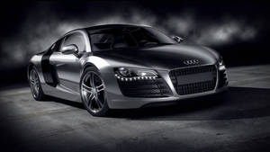 銀色奧迪R8跑車在黑暗煙霧瀰漫的攝影棚中，帶有戲劇性燈光。 — Audi R8 GIF 壁紙