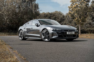 銀色Audi e-tron GT電動車停泊在秋季林蔭大道上。 — 奧迪 GIF 壁紙
