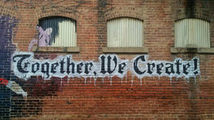 磚牆上的塗鴉壁畫，寫著 Together We Create