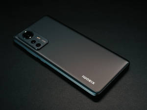 黑色Xiaomi智能手機，帶相機模組，置於紋理表面上。 — Xiaomi 壁紙