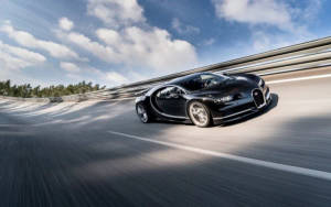 黑色Bugatti Chiron在陽光明媚的天空下在彎曲的道路上飛馳。