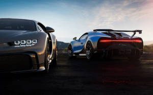 兩輛Bugatti超級跑車在日落時停在山路上。