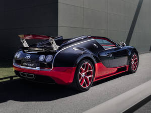 黑色和紅色的Bugatti Vitesse超級跑車停放在戶外灰色牆壁附近。
