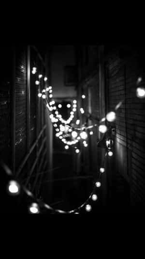 燈串在夜間照亮狹窄小巷，帶有柔和發光的散景。 — 復古 壁紙