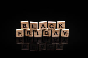 黑色反光表面上用木製Scrabble字母牌拼出的Black Friday。