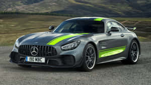 灰色Mercedes-AMG GT，帶有綠色賽車條紋，停泊在山丘附近的碎石地上。 — 汽車 壁紙