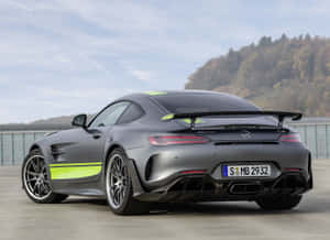 啞光灰色梅賽德斯-AMG GT R 帶有螢光綠色條紋，停放在森林覆蓋的山丘附近，正值日落時分。 — 汽車 壁紙