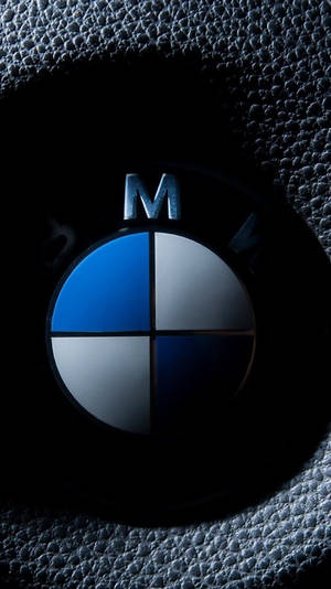 黑色皮革內飾上的 BMW M 標誌，帶有藍色和銀色點綴。