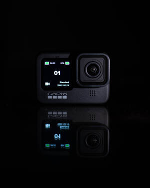 一部黑色GoPro相機在反射表面上帶有發光螢幕細節。