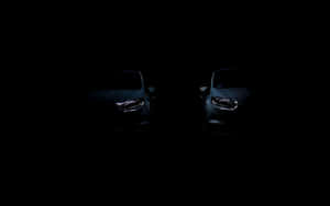兩輛在完全黑暗中帶有發光車頭燈的汽車。