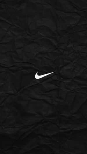 白色Nike標誌在黑色皺紙背景上。