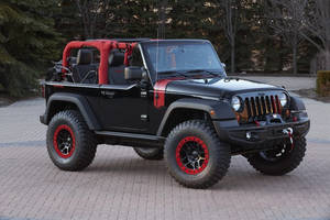 黑色Jeep Wrangler，帶有紅色飾邊，停在日落時分的鋪砌車道上。