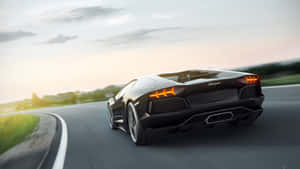 黑色林寶堅尼 Aventador 在日落時分於蜿蜒道路上疾馳。