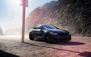 日落時分，黑色BMW M4雙門轎跑車停在岩石懸崖旁的塵土路上。